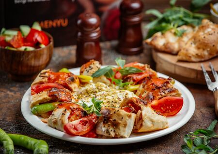 Beyti wrapped kebab topped with tomato sauce, served with tomato, pepper, yoghurtの写真素材
