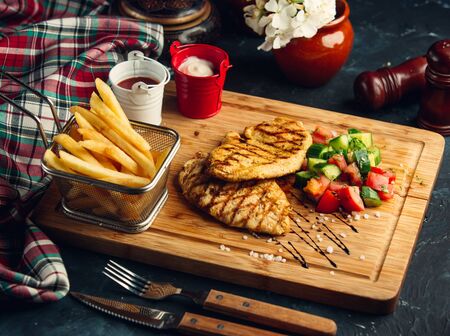 Grilled chicken fillet serve with fresh salad and french fries, mayo and ketchupの写真素材