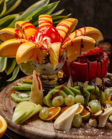 Fruit plate of banana, apple, kiwi, orange served with ice creamの写真素材