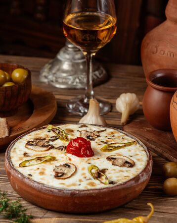 Kebab with melted cheese and grilled vegetables on top in pottery panの写真素材