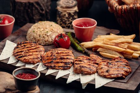 Grilled chicken patties with pilaff, french fries and ketchupの写真素材