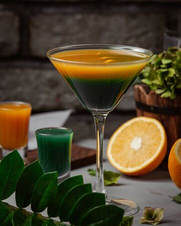 Exotic cocktail in cocktail glass with orange and green juiceの写真素材