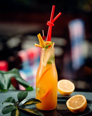 Orange juice with orange slices and red pipes in bottleの写真素材