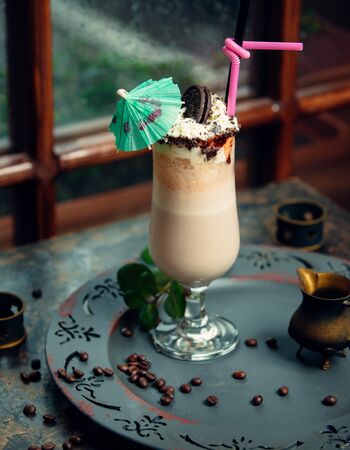 Iced latte with whipped cream, oreo on top, pink straw, cocktail umbrellaの写真素材