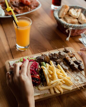 Lamb tikka kebab on bamboo skewers served with fries, pickled cabbage, saladの写真素材