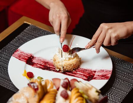 Dessert plate with portioned cheesecake with whipped cream and raspberry on topの写真素材