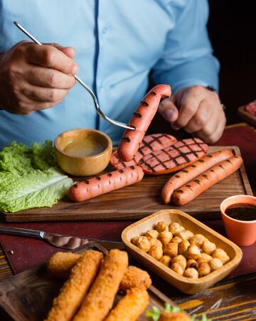 Men eating grilled sausages with roasted chickpeas, and croquettesの写真素材