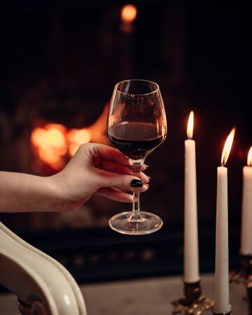 A glass of red wine surrounded with candles in romantic atmosphereの写真素材
