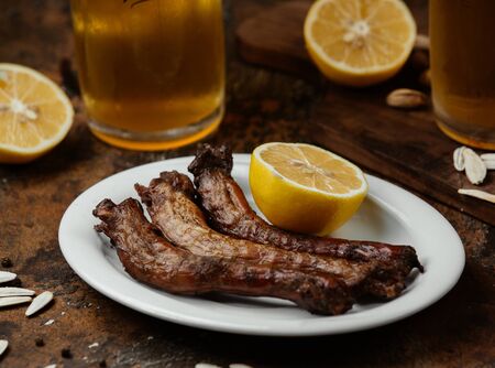 Three pieces of grilled chicken neck served with lemon and beverageの写真素材