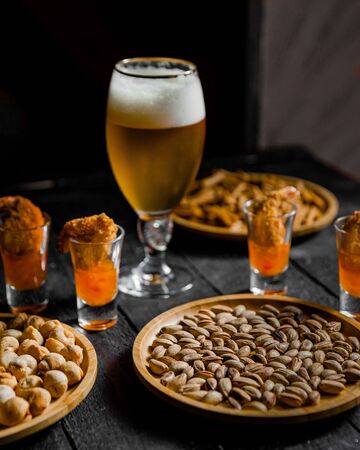 beer served with bean and dried nuts on the tableの写真素材
