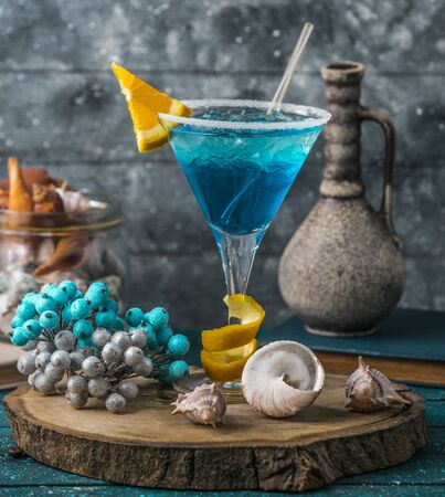 blue lagoon cocktail in martini glass garnished with orange pieceの写真素材