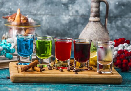 five shot glasses with colorful drinks on wood boardの写真素材