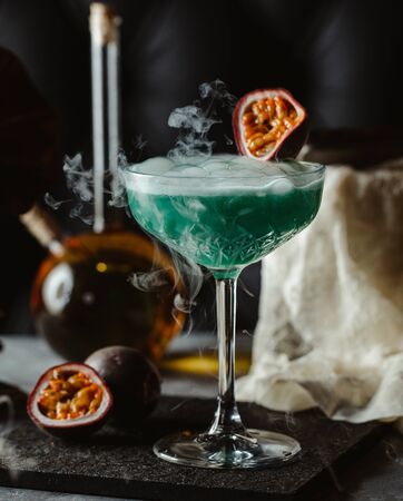 smoked green drink with ice cubes, garnished with passionfruitの写真素材