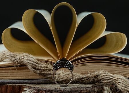 a ring with burgundy stones in front of open book, rustic styleの写真素材