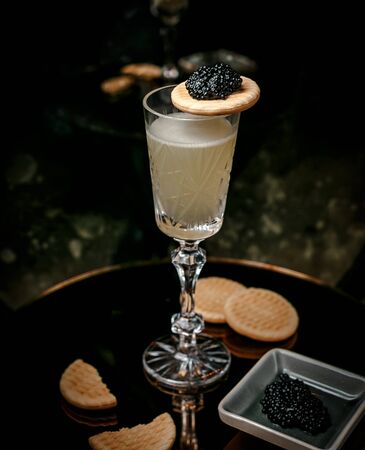 white wine in crystal glass served with black caviar and cookiesの写真素材