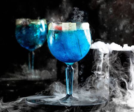 blue lagoon with cucumber slice next to smoked glassの写真素材