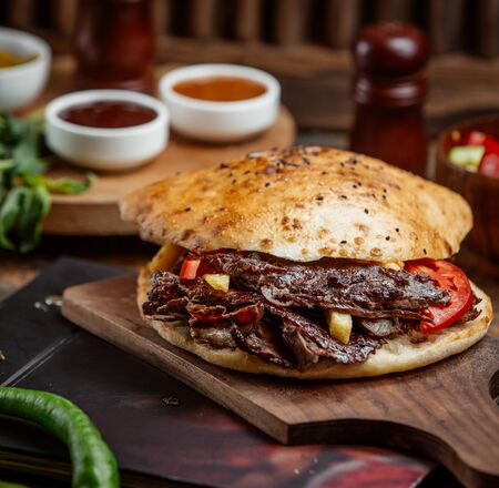 beef doner with bread stuffed with potato, fries served on wood boardの写真素材