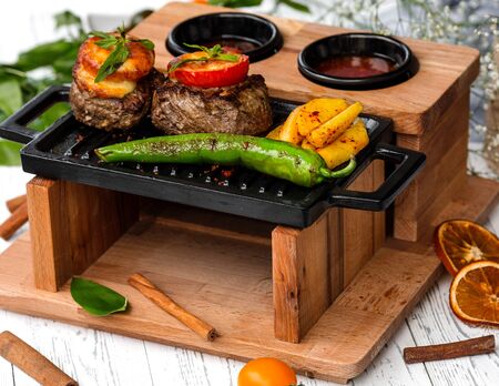 beef steaks topped with tomato and cheese served in creative wood servings
