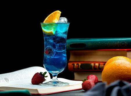 blue cocktail with blackberry, orange slice, strawberry and iceの写真素材