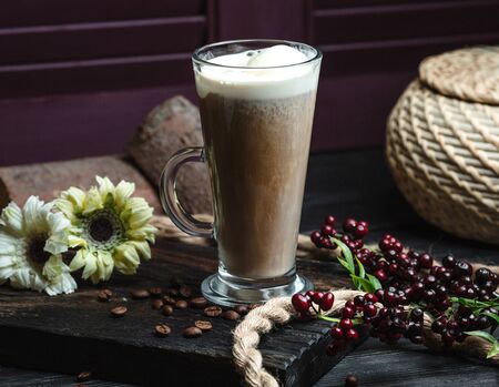 a glass of latte with foam decorated with coffee beans and flowers