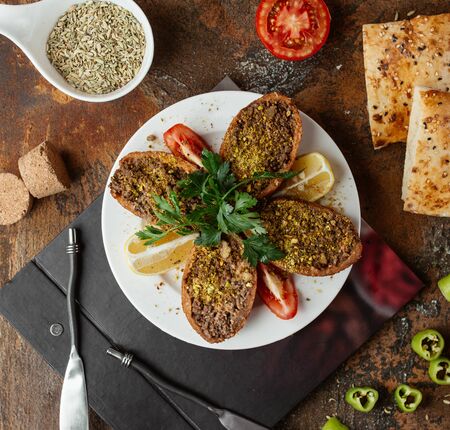 turkish stuffed meatball ichli kofte served with lemon, parsley and tomatoの写真素材