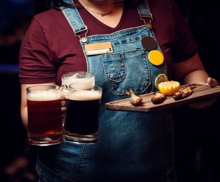 woman holding three beer mugs and platter of three smoked fish with lemonの写真素材