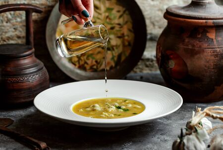 woman pouring vinegar into dushbara dumplings soupの写真素材