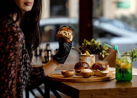 woman holding mini burger wearing black glovesの写真素材