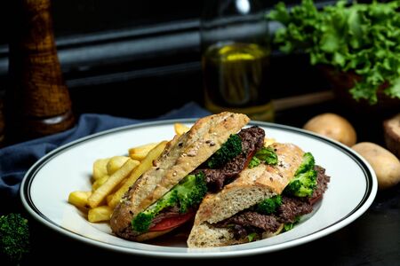 beef sandwich with broccoli, tomato in bread served with fries