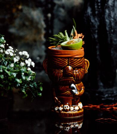 a creative glass of cocktail garnished with herbs and limeの写真素材