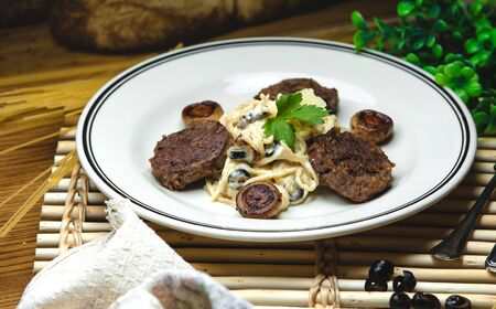 spaghetti in a creamy sauce with fried mushrooms and meatの写真素材