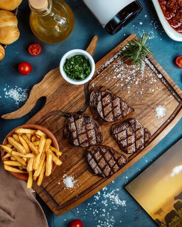 four small steak pieces served with french fries and dicedの写真素材