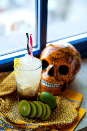 a glass of lime and kiwifruit cocktail next to orangeの写真素材