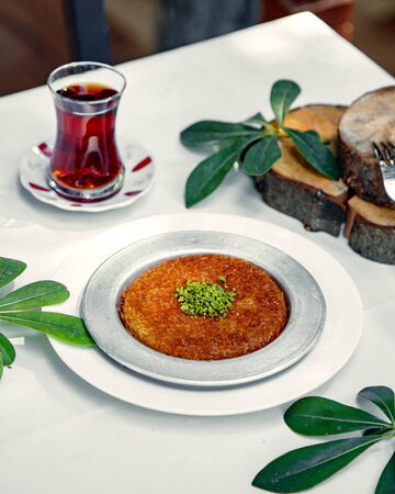 turkish kunefe dessert topped with pistachio served with teaの写真素材