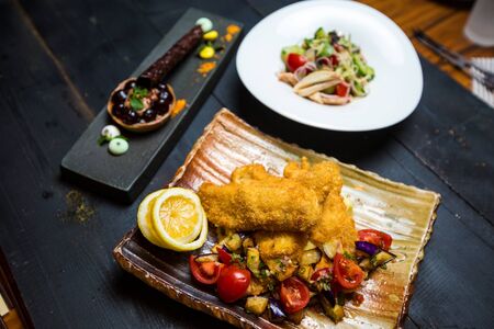 crispy fried fish served with fried aubergine and fresh tomato