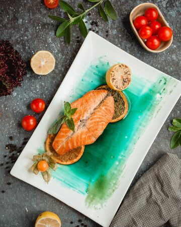 fried salmon with lemon slices and tomatoesの写真素材