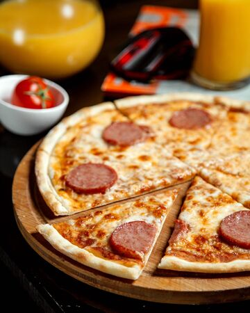 pizza with sliced sausages and orange juiceの写真素材