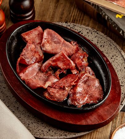 raw cooked meat slices served in iron cast panの写真素材