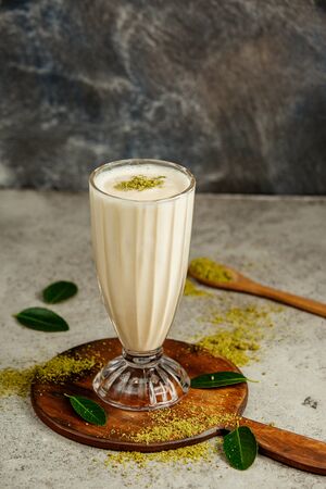a glass of vanilla milkshake with pistachio sprinklesの写真素材