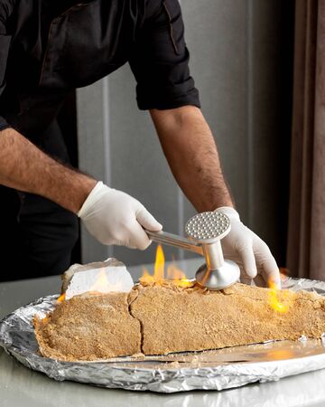 chef breaking burning salt crusted fish with steel tenderizerの写真素材