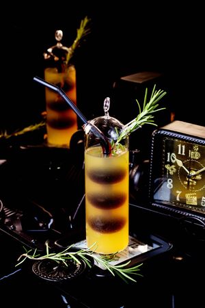 unique glass of two colored cocktail garnished with rosemarine