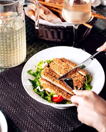 woman cutting sesame crusted chicken served with saladの写真素材