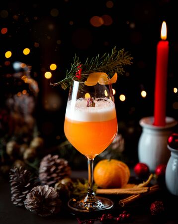 a glass of orange drink decorated with a tree branchの写真素材