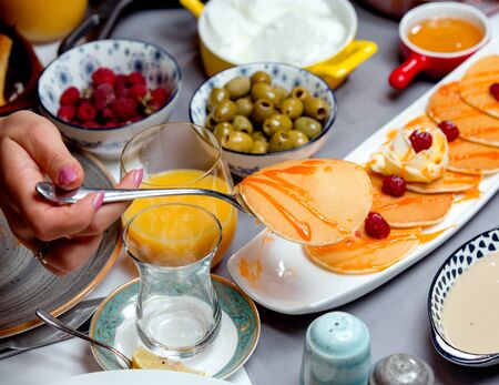 pancakes with jam, olives, a glass of juice and raspberriesの写真素材