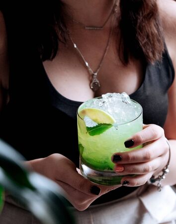 girl holds a glass of mojito with lemon and mintの写真素材