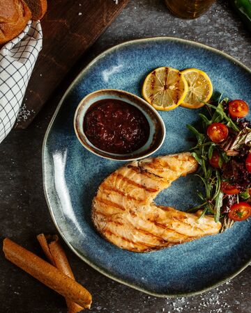 fried salmon fillet with vegetables and lemon slicesの写真素材