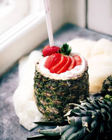 milkshake with strawberries served inside pineappleの写真素材