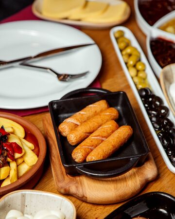 fried sausages on a tray with french fries and olivesの写真素材