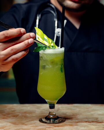 green apple cocktail garnished with green apple slice and mintの写真素材