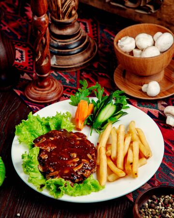 meat with mushrooms in sauce and french friesの写真素材